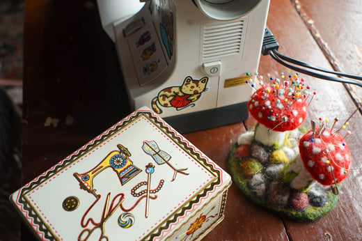 A wool mushroom pincushion and a vintage tin of sewing notions