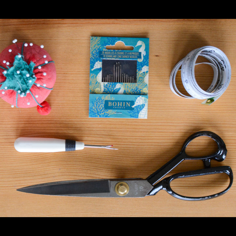 Scissors, thread, and a spool of thread on a wooden surface